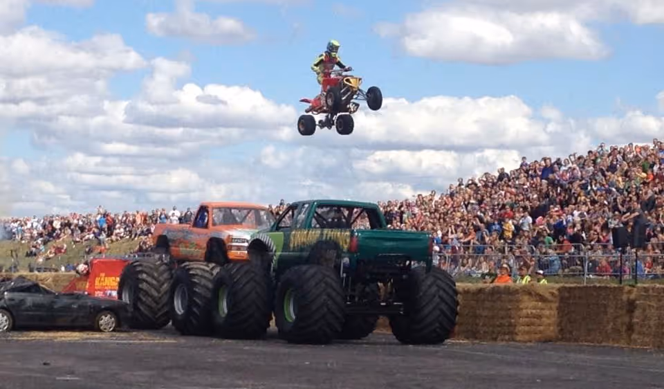 A quad bike jumping over a monster truck