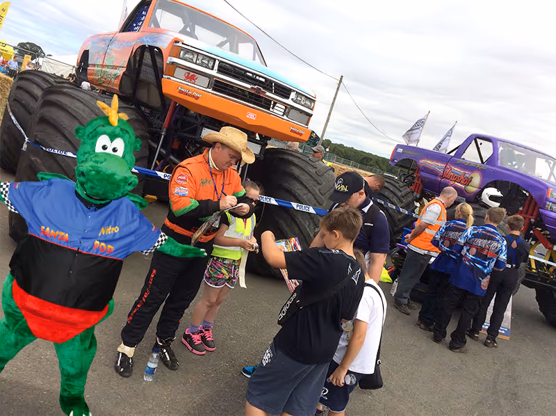 Children meeting drivers and the mascot in front of the trucks at the Pit Party