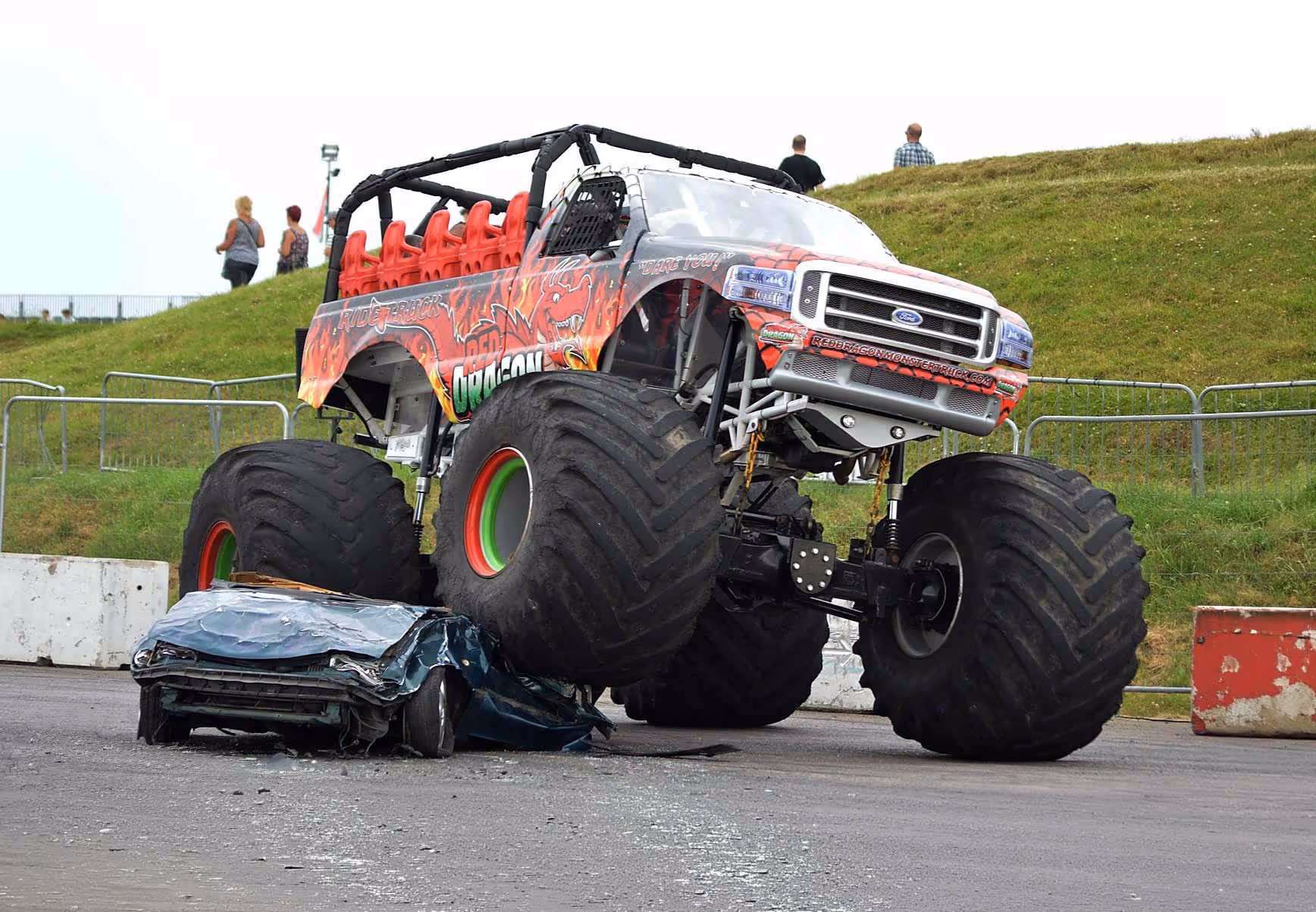 The passenger-ride monster truck parked on top of a crushed car