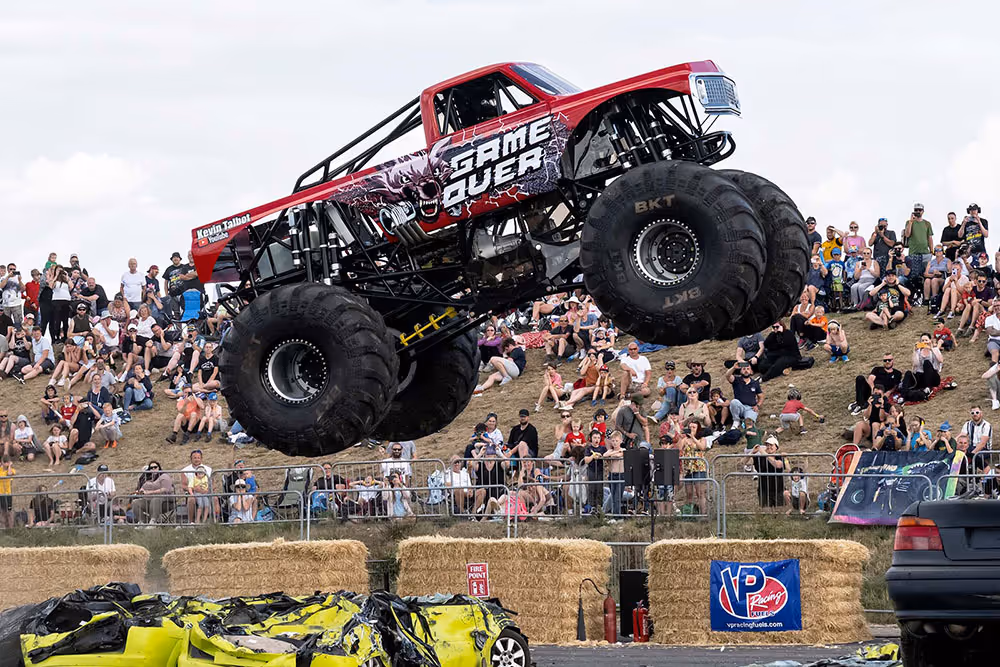 Game Over jumping over a row of crushed cars in front of the crowd