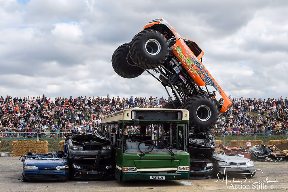 Podzilla standing up on its rear wheels on top of a green bus